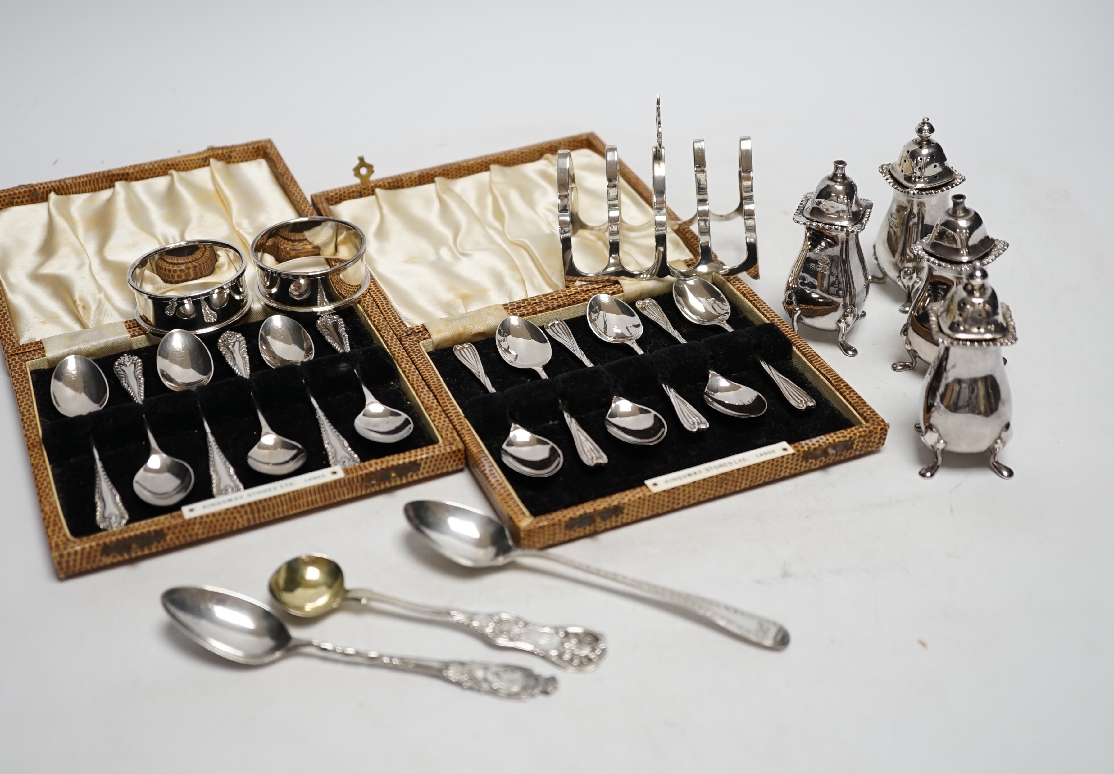 Two cased sets of six silver coffee spoons, a set of four silver condiments, two silver napkin rings, silver toastrack, etc.